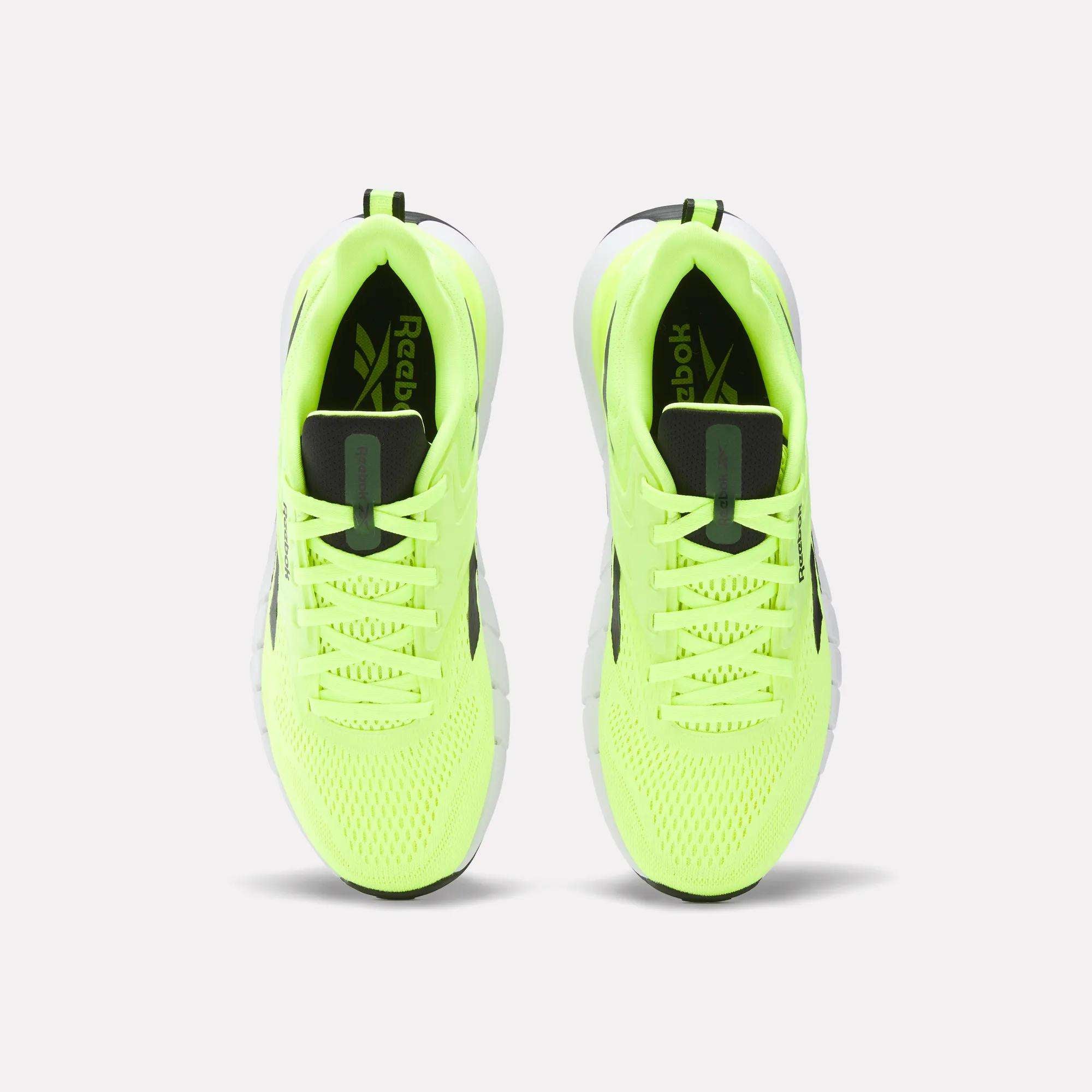 Top view of a pair of Reebok Men's Nano Gym Training Shoes in bright yellow-green with black and white accents, black laces, and mesh toe detailing, placed side by side on a white background.