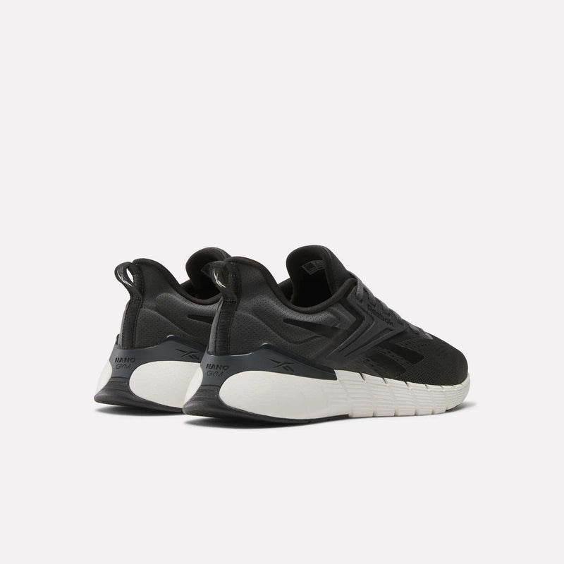 A pair of black Reebok Men's Nano Gym Training Shoes with white chunky soles is shown from a rear side angle against a plain light background, featuring heel pull tabs and a sleek, modern design.