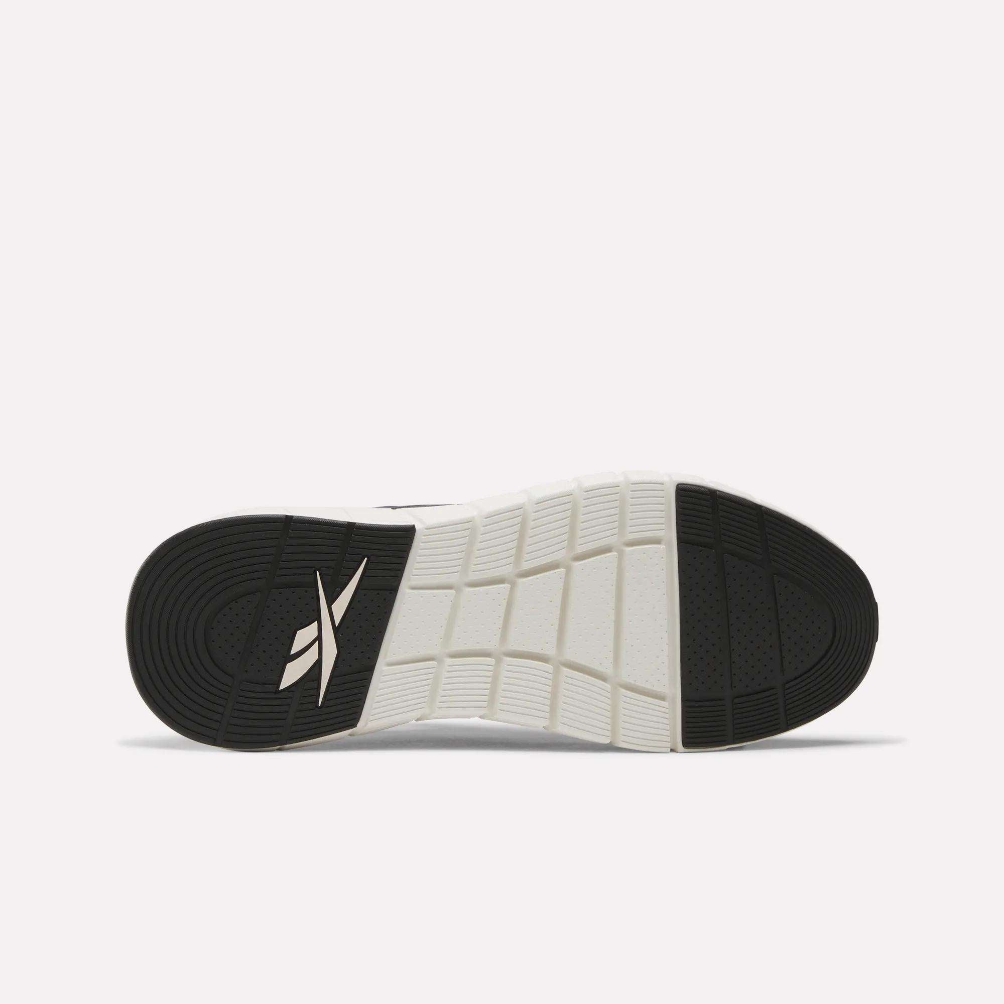The image shows the black and white rubber outsole of Reebok Men's Nano Gym Training Shoes, featuring a grid pattern and the Reebok logo near the heel.