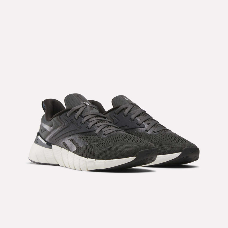 A pair of Reebok Men's Nano Gym Training Shoes in dark gray with white soles and mesh uppers, shown on a light background, angled to highlight both the side and front.
