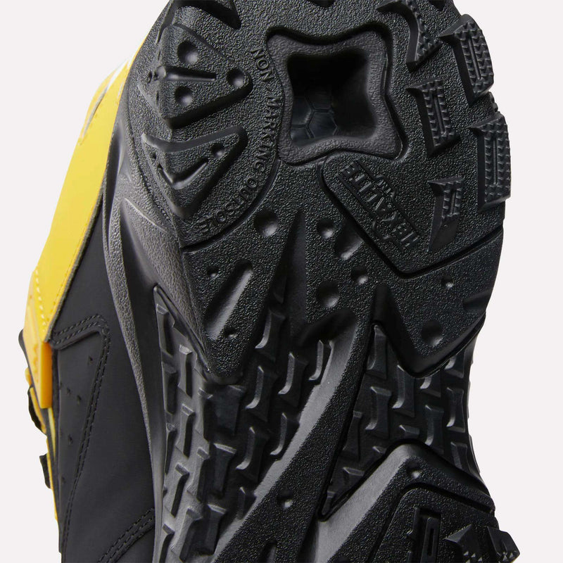 Close-up of the Brutus Low Shoes by Reebok, featuring a black rubber outsole with a rugged tread pattern and part of the yellow and black upper, showcasing their bold, street-ready style.