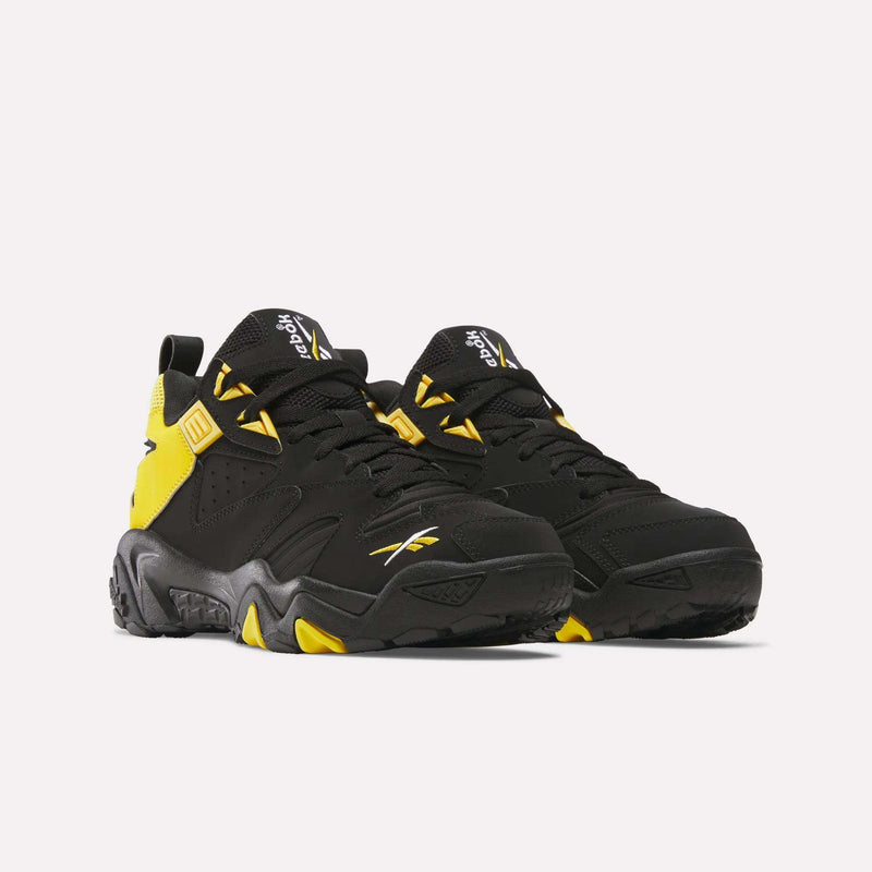 A pair of Brutus Low Shoes by Reebok in black and yellow, featuring chunky soles, yellow accents on the heel and sides, with visible Reebok logos. Heritage style photographed side by side on a white background.