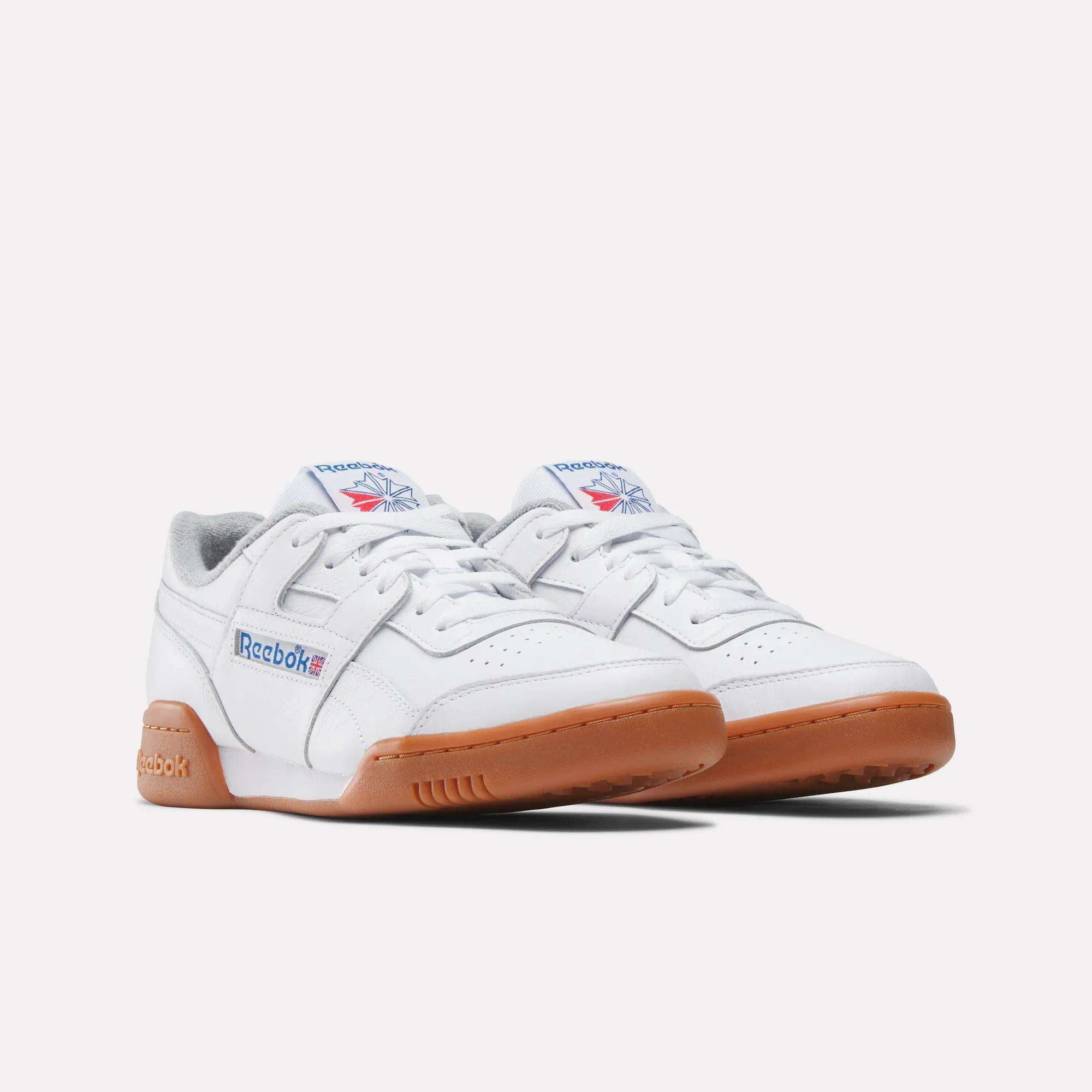 Women's Workout Plus Shoes by Reebok in white feature gum soles, blue and red Reebok branding on the side and tongue, and a gray inner lining, capturing classic '80s fitness style against a plain white background.