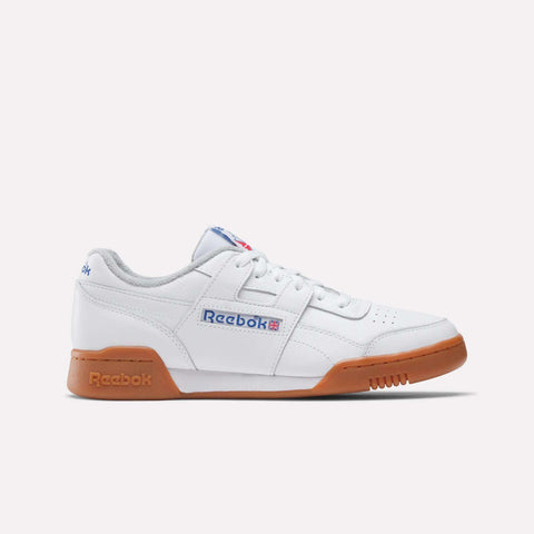 The Reebok Women's Workout Plus Shoes feature a white upper, gum sole, blue and red side logo, and white laces—shown in profile on a plain light background for classic '80s-inspired style.