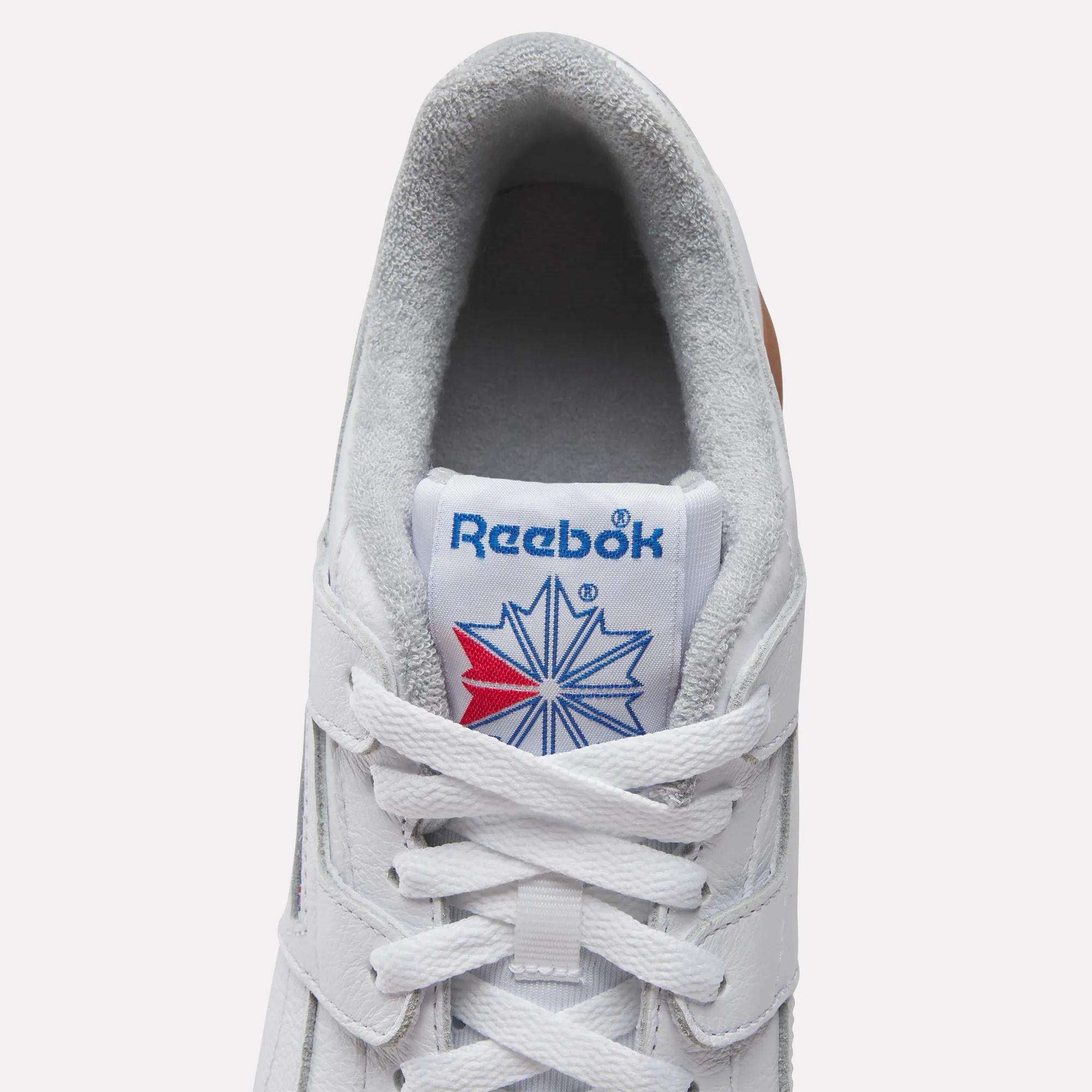 Top view of Reebok Workout Plus Shoes features gray lining, white laces, and a blue Reebok logo with a red and blue star on the tongue—a classic tribute to '80s fitness heritage.