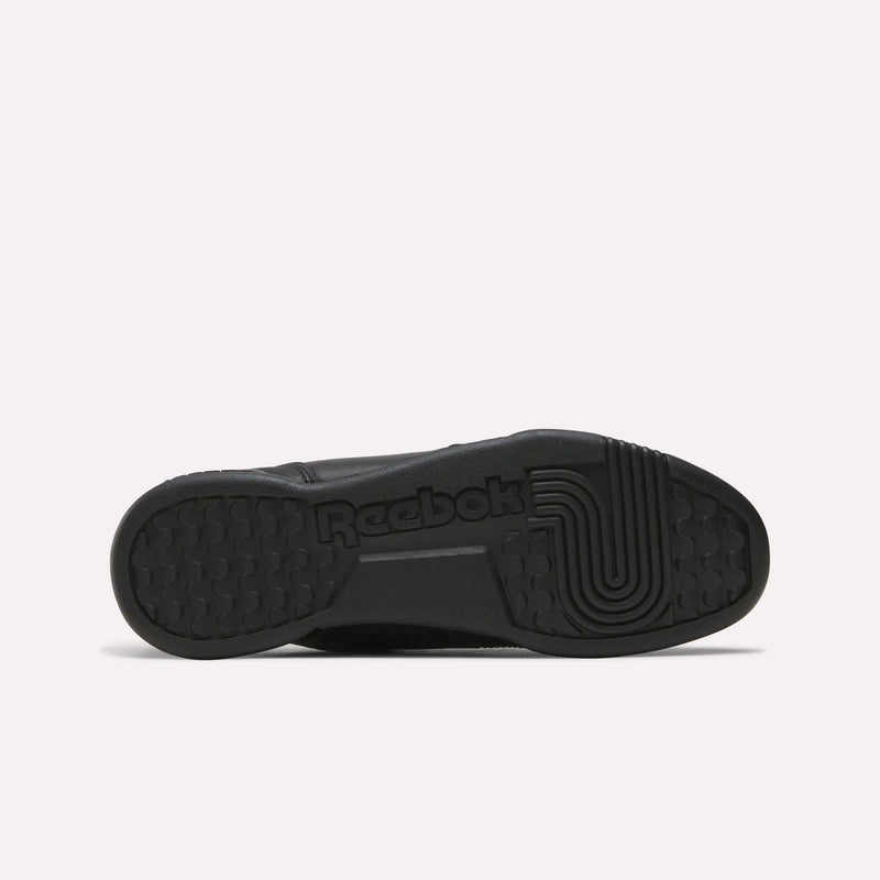 The image shows the black rubber sole of Reebok Workout Plus Shoes lying flat, featuring the Reebok logo and a geometric grip pattern on the bottom, echoing classic 1980s fitness style.
