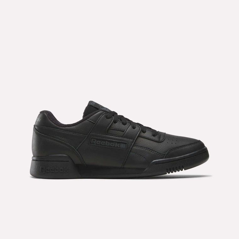 The Reebok Workout Plus Shoes are black low-top sneakers with a lace-up design, textured rubber sole, and embossed logo on the side, featuring a sleek, minimal ’80s-inspired fitness style.