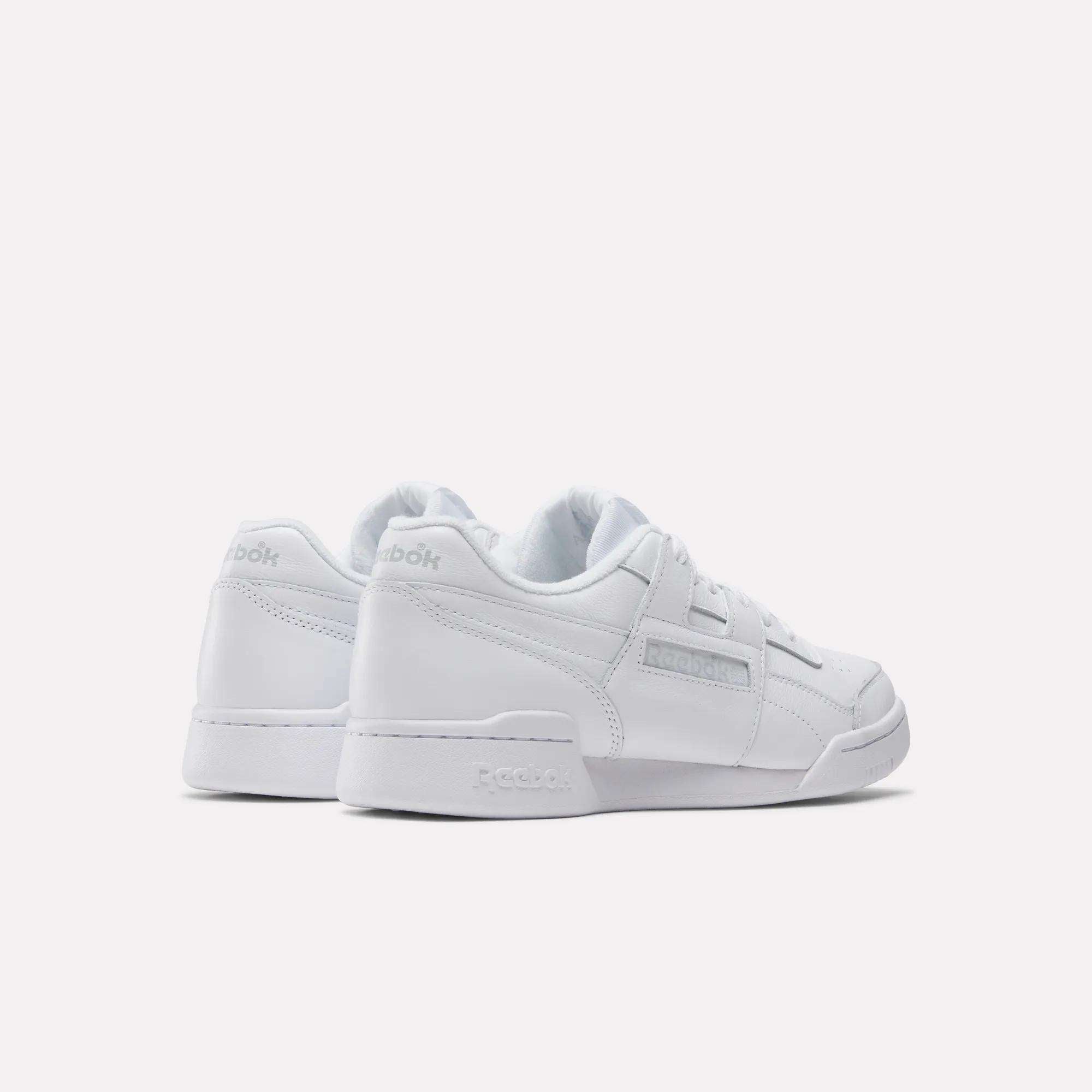 A pair of Reebok Workout Plus Shoes are displayed on a white background, angled to reveal both side and back views. These low-top sneakers highlight subtle branding and the classic '80s fitness style from Reebok.