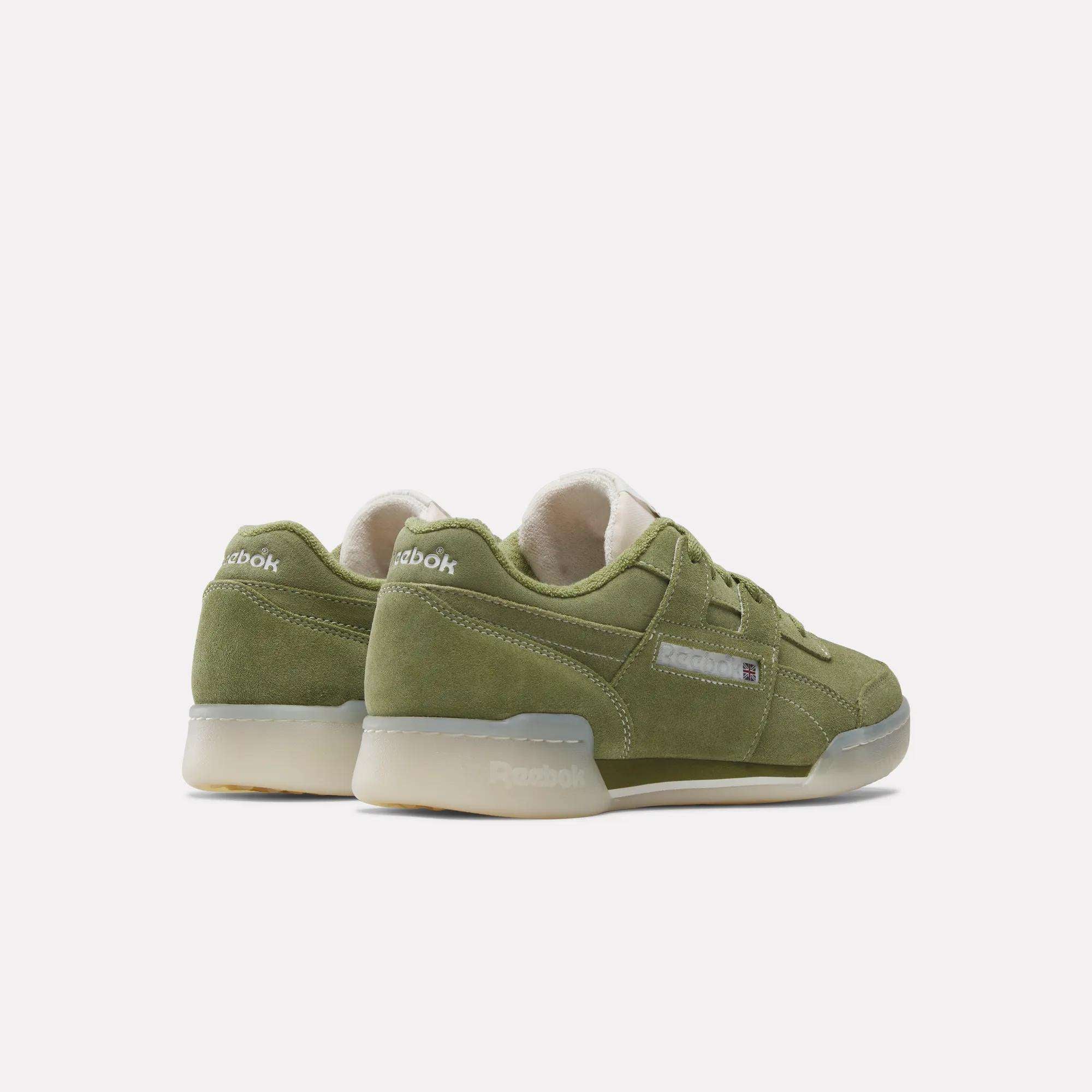 A pair of Reebok Workout Plus Shoes in olive green suede with beige midsoles and gum outsoles, shown angled to highlight their classic '80s fitness style from the side and back views.