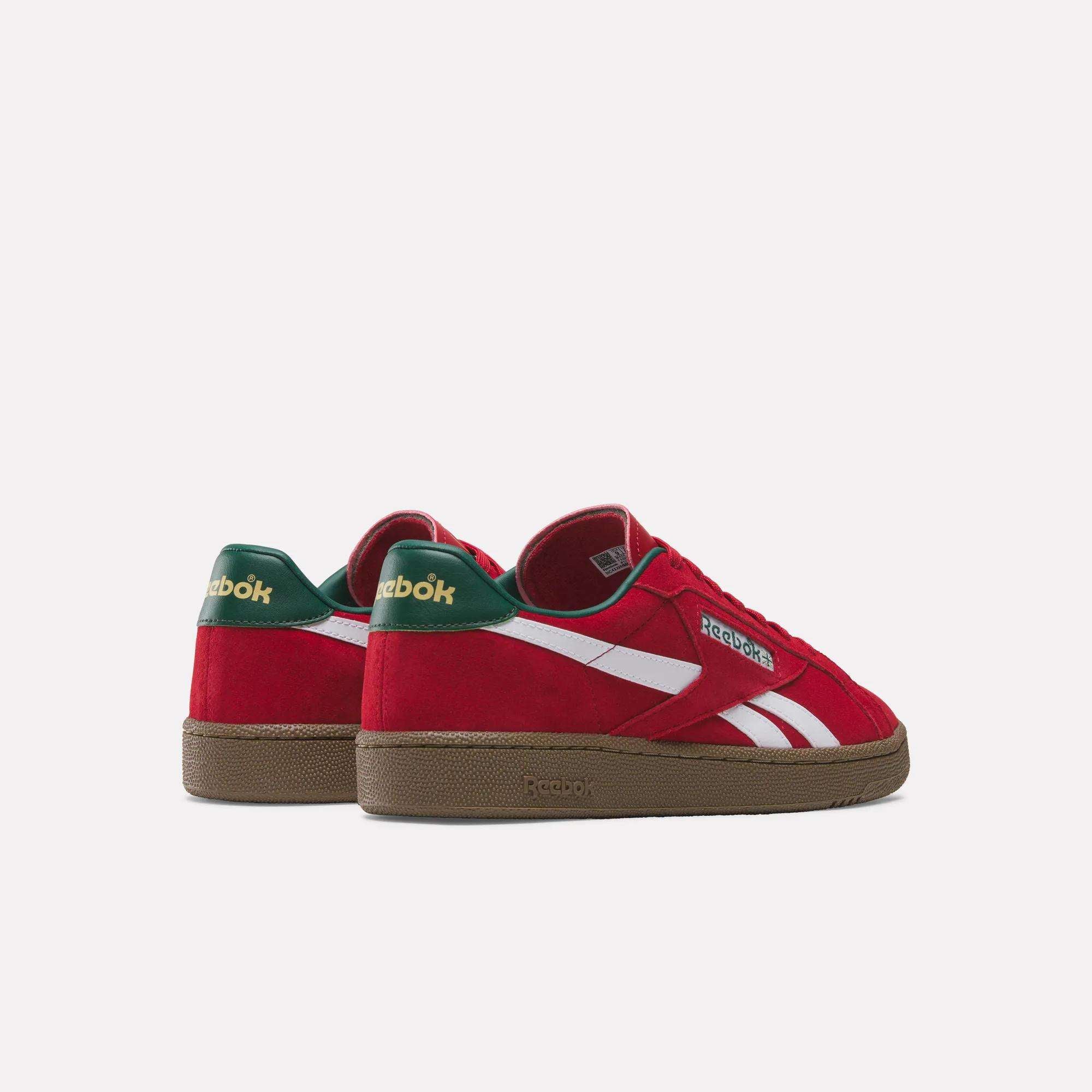 The Reebok Club C Grounds UK Shoes feature a red design with white side stripes, green heel tabs, and gold Reebok branding on the heel—perfect casual tennis-style shoes displayed on a plain light background.