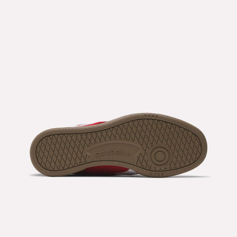 The image shows the sole of Reebok Club C Grounds UK Shoes from the bottom, featuring a brown herringbone tread and embossed Reebok logo. A red upper edge hints at the casual, tennis-inspired style of these shoes.