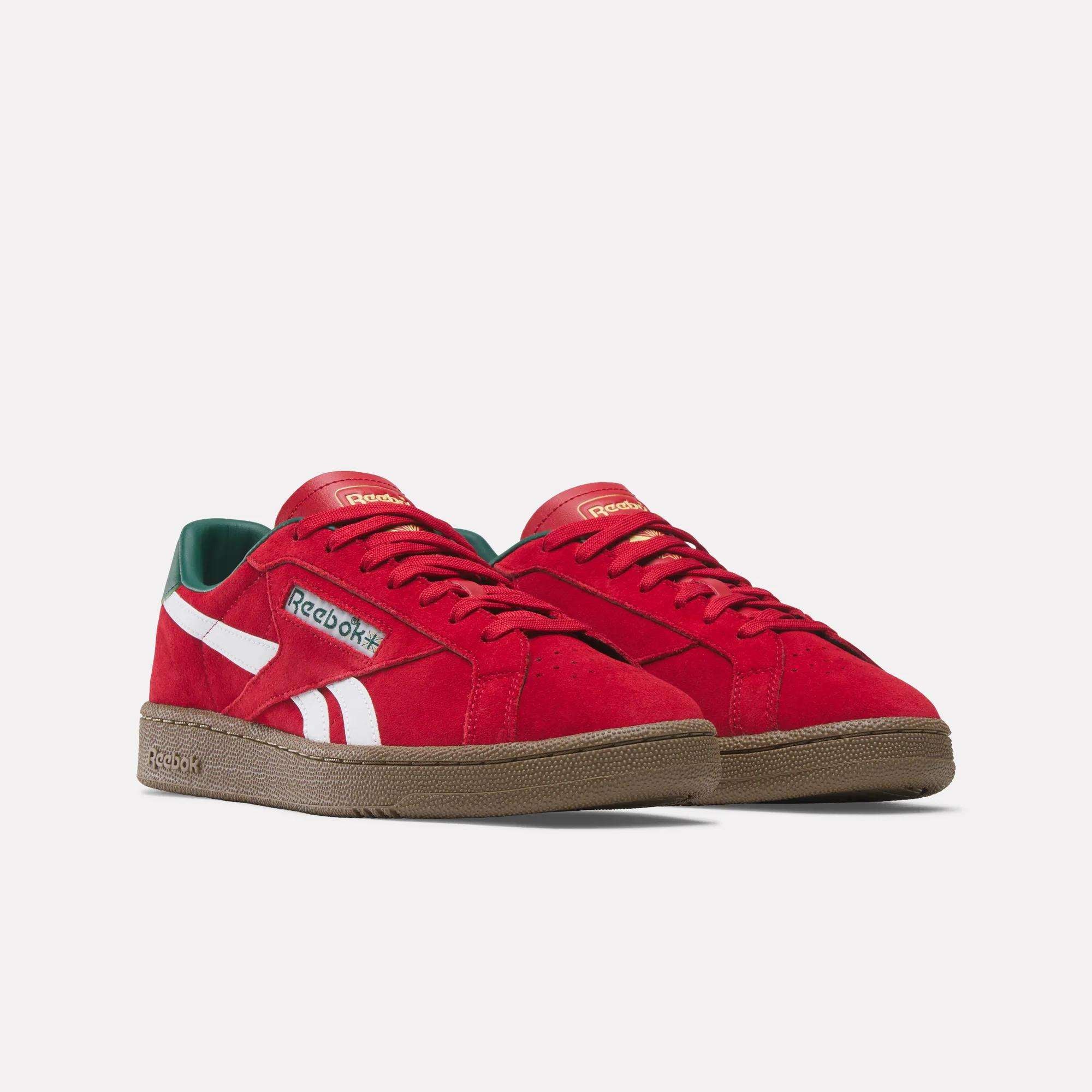 The Reebok Club C Grounds UK Shoes feature red uppers, white stripes, green inner lining, and brown rubber soles—classic tennis style sneakers displayed on a plain white background.