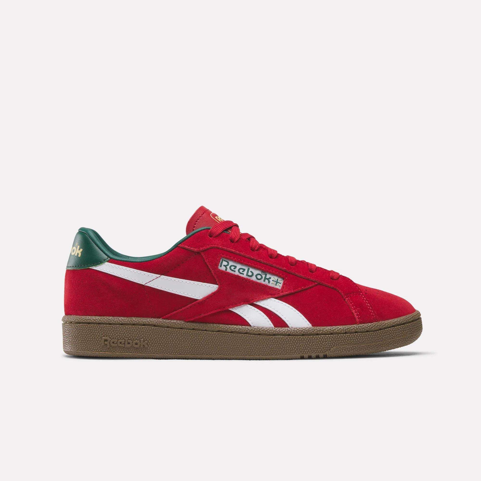 The Reebok Club C Grounds UK Shoes feature a red design with white stripes, green heel and tongue accents, and a brown sole—classic tennis style in a casual side profile for fans of iconic Reebok sneakers.