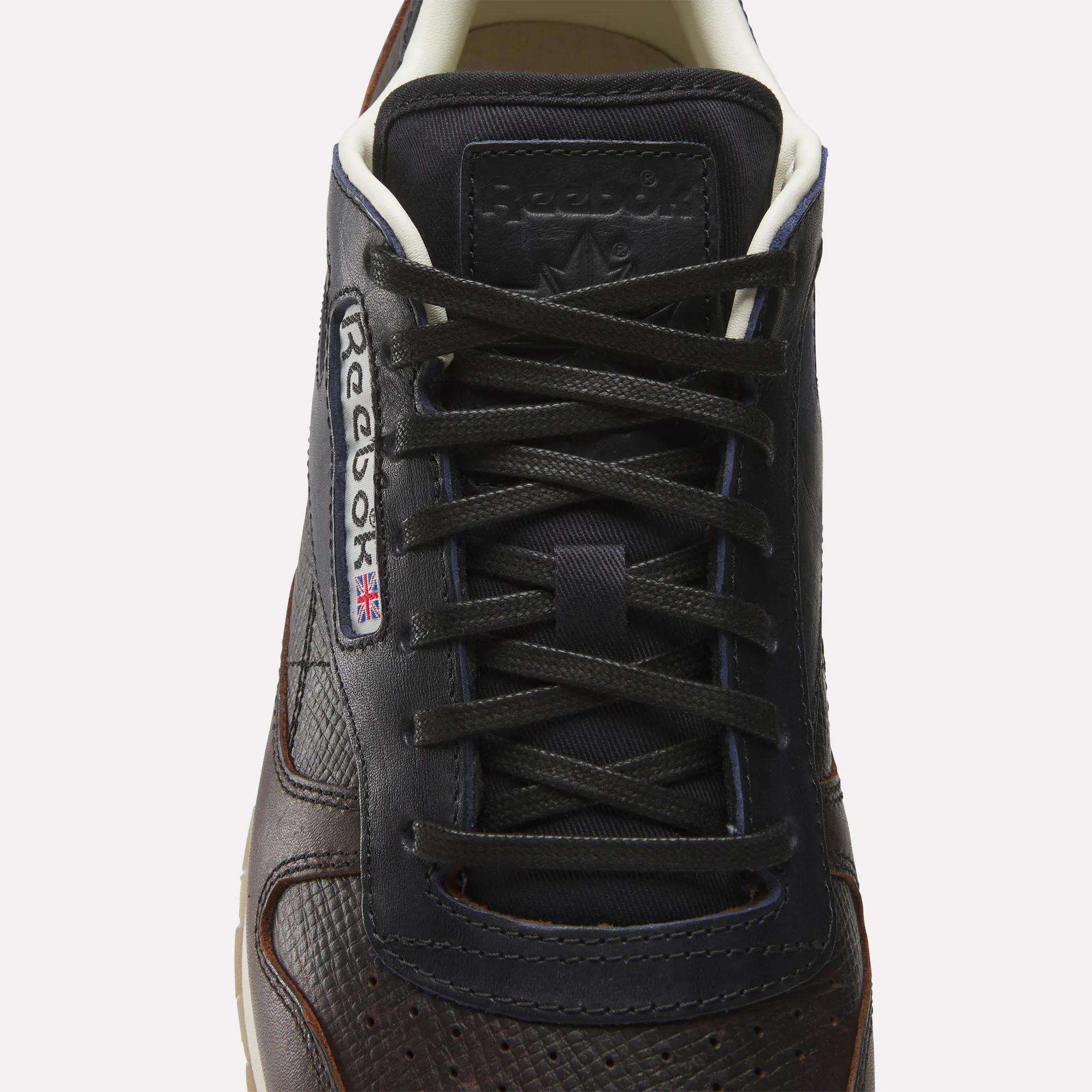 A close-up, top view of the Reebok x C.F. Stead Classic Leather Shoes in dark brown full-grain leather, featuring black laces and the Reebok logo with a UK flag on the side.