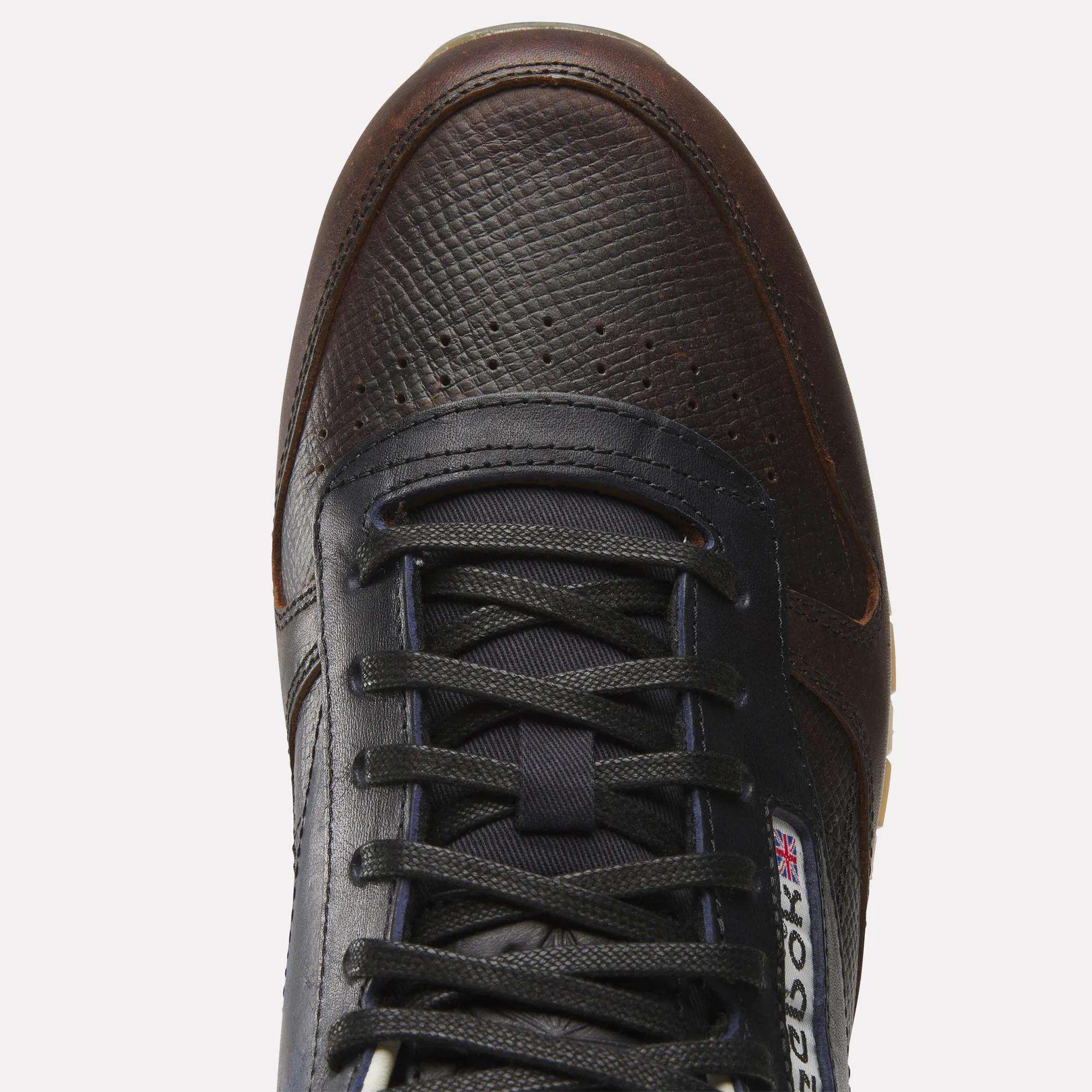 Top view of the Reebok x C.F. Stead Classic Leather Shoes in dark brown and black, featuring a textured full-grain leather upper, black laces, and a visible Reebok logo with the British flag near the tongue.
