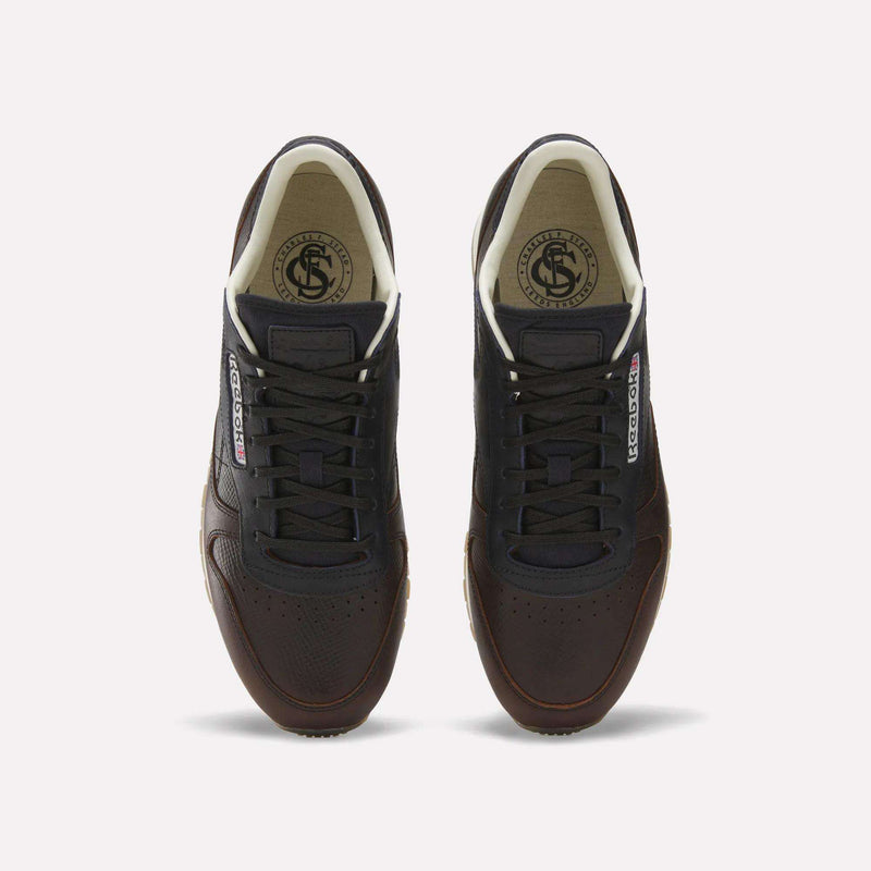 The Reebok x C.F. Stead Classic Leather Shoes feature dark brown luxe leather, black laces, white inner lining, and Reebok logos on the tongue and side, shown from above against a plain white background.
