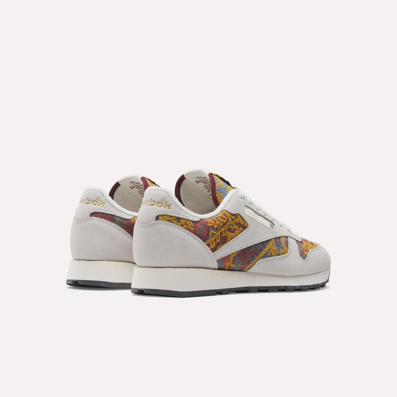The Reebok Classic Leather 1983 Vintage Shoes feature white suede uppers, gold heel branding, and colorful patterned accents in red, orange, and yellow. Shown from back and side on a white background.