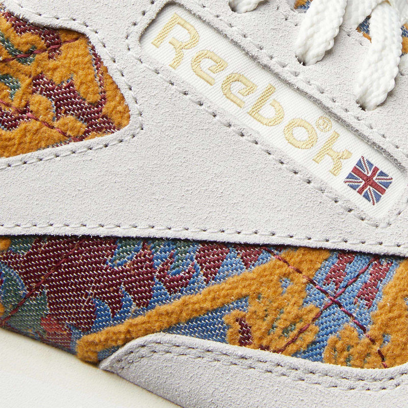 Close-up of Reebok Classic Leather 1983 Vintage Shoes, featuring a soft beige suede upper, white laces, and colorful accents. The Reebok logo and UK flag tag give these sneakers a nostalgic touch for vintage running shoe enthusiasts.