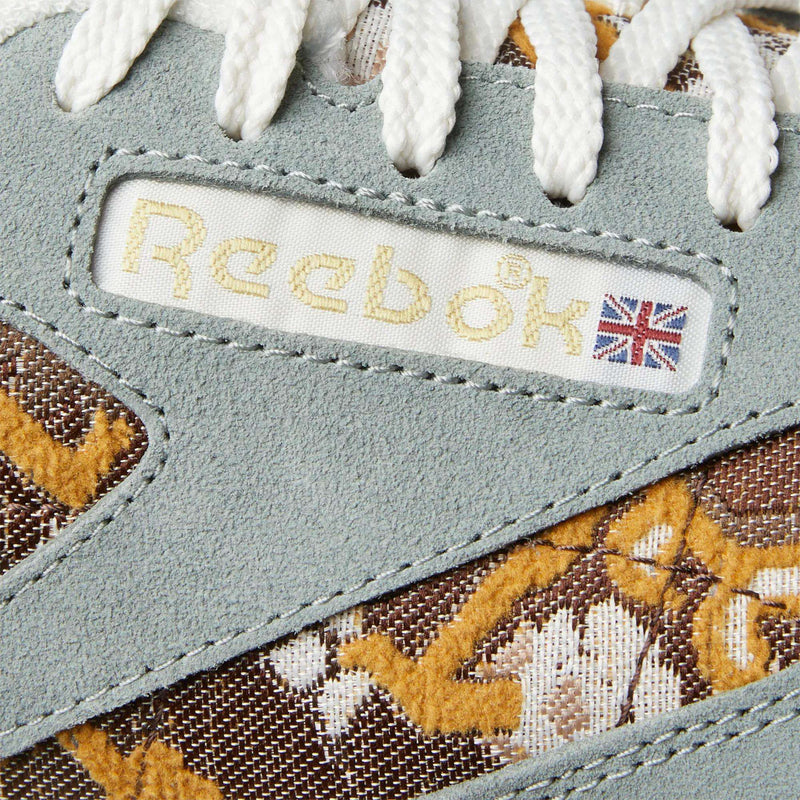 Close-up of Reebok Classic Leather 1983 Vintage Shoes with light gray suede, brown floral-patterned fabric inspired by Persian rugs, white laces, and a fabric label featuring the Reebok logo with a small Union Jack.
