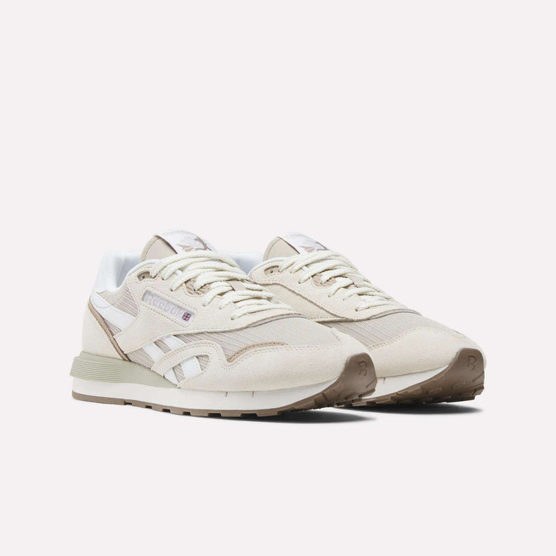 A pair of Reebok Classic Nylon 89 Shoes in beige with white accents, featuring suede and mesh details, a cushioned midsole, and a gum rubber sole, are positioned side by side on a plain white background.