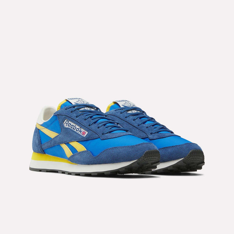 A pair of blue Reebok Aztec II Shoes with yellow and white accents, crafted in vintage running style nylon and suede, featuring the Reebok logo on the side and tongue, displayed against a plain white background.