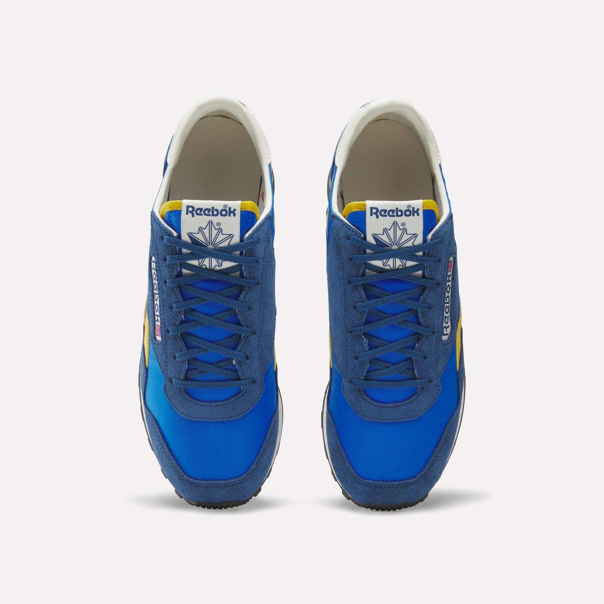 A pair of blue Reebok Aztec II Shoes with suede and mesh uppers, yellow and white accents, plus white tongue labels showing the Reebok logo, viewed from above on a white background—ideal for vintage running shoe fans.