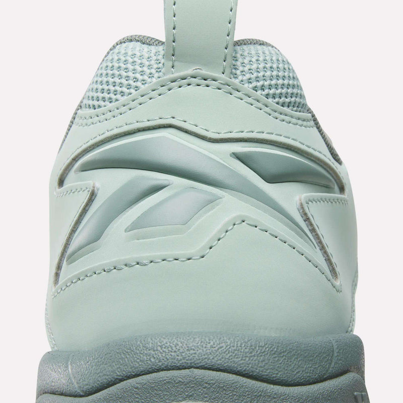 Close-up of the back of a light green Brutus Low Shoe by Reebok, featuring textured fabric, smooth synthetic overlays, and a stylish heel design—ideal for adding street style to your look.