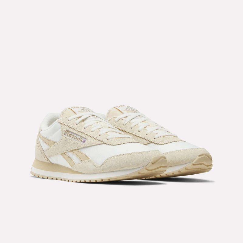 Reebok Women's Classic AZ Shoes in beige and white are shown on a plain white background, featuring a retro low-profile design with suede and mesh panels, beige soles, and Reebok branding on the side.