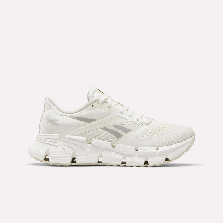 Side view of a white Reebok Women's FloatZig 2 Running Shoe featuring a mesh upper, unique angular outsole, and energy-return cushioning for comfort.