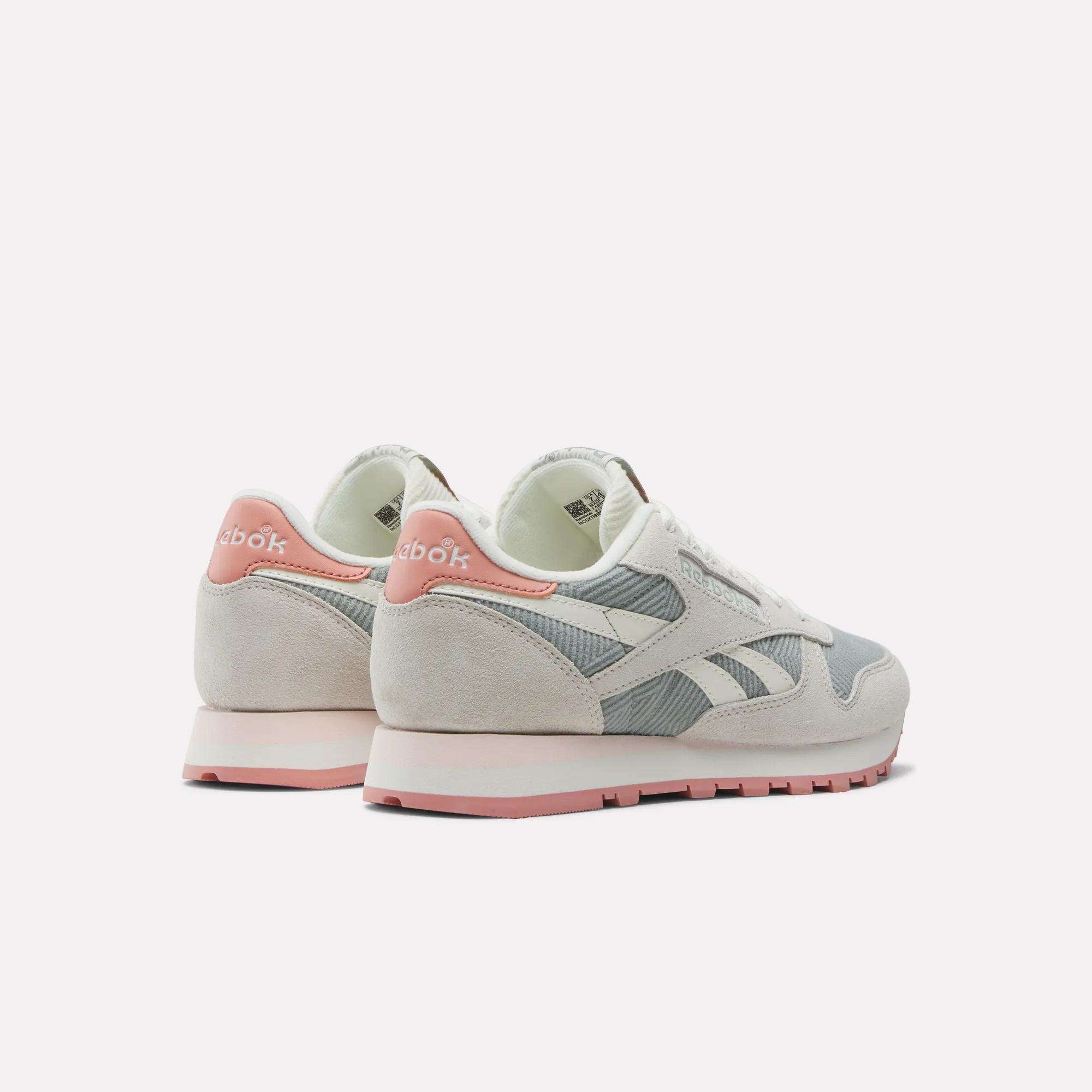 A pair of Reebok Women's Classic Leather Shoes in beige and light gray with pink accents, shown from the back and side on a white background.