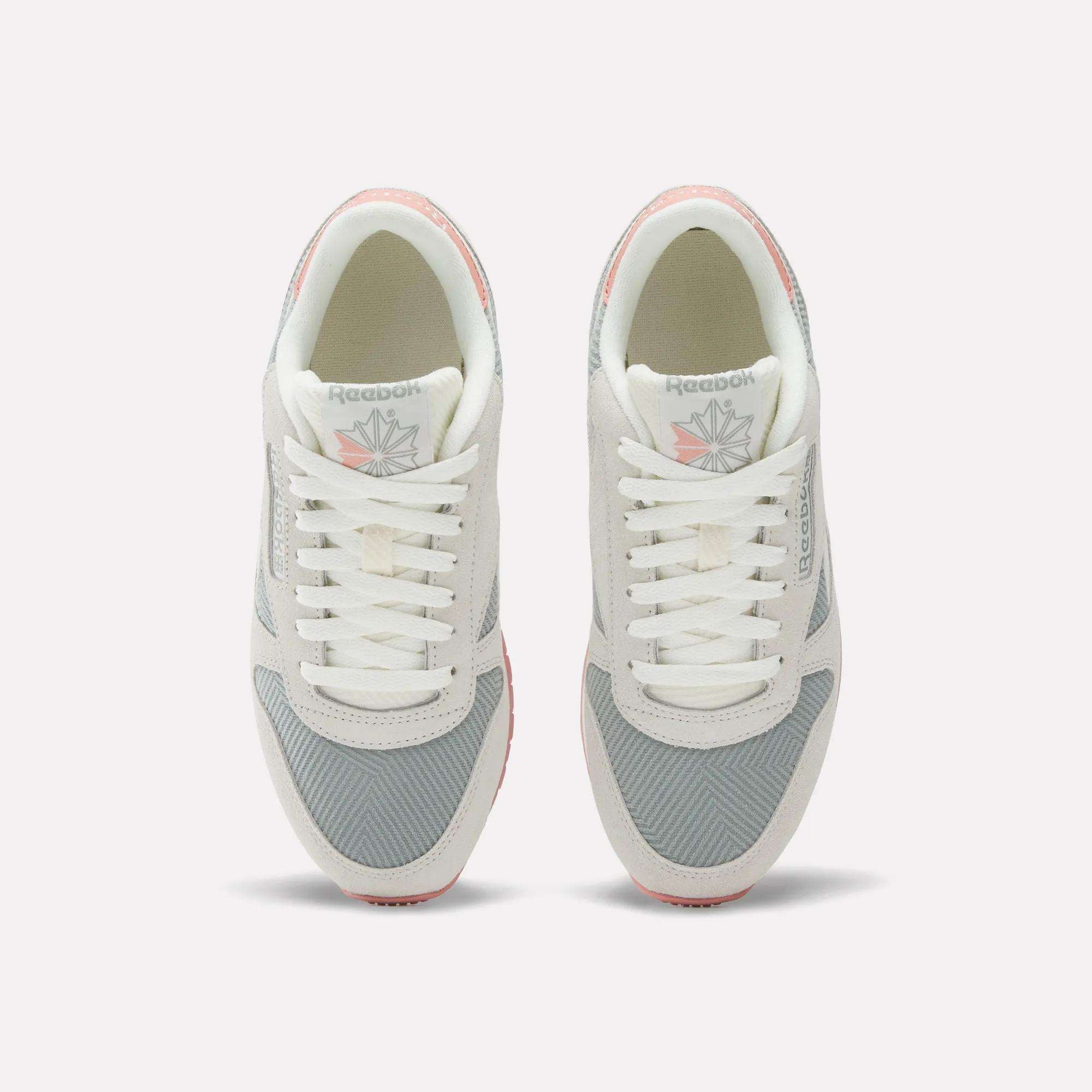 Top view of Reebok Women's Classic Leather Shoes in light gray and white with pink accents, featuring laces, mesh fabric, and the Reebok logo on the tongue.