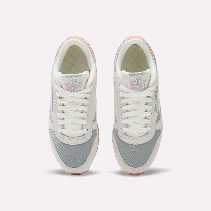 Top view of Reebok Women's Classic Leather Shoes in light gray and white with pink accents, featuring laces, mesh fabric, and the Reebok logo on the tongue.