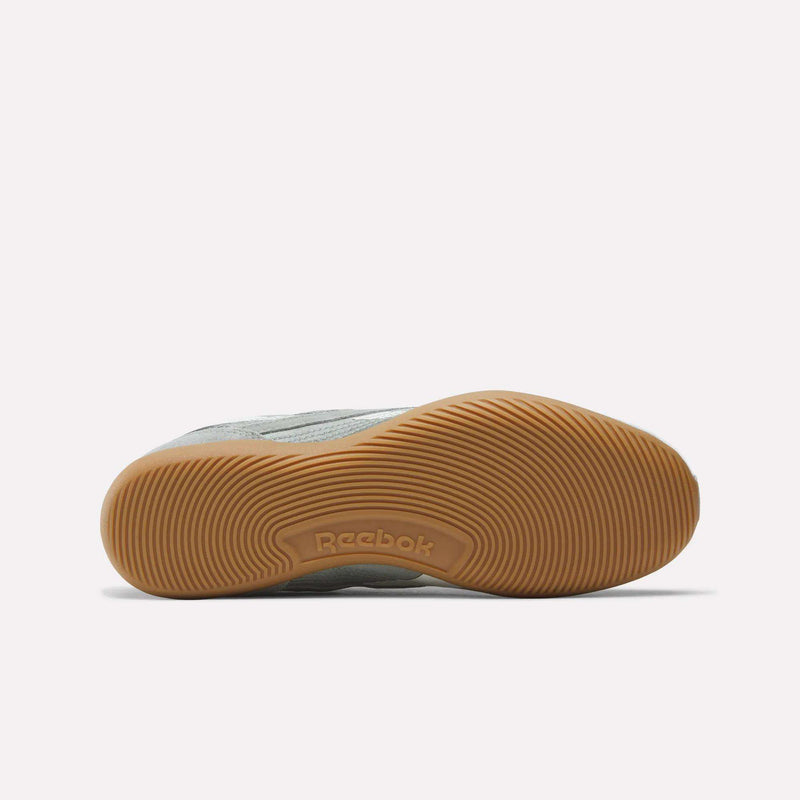 The image shows the bottom view of Reebok Women's Ultra Lo Shoes in light gray, featuring a textured light brown rubber sole with circular tread patterns and the Reebok logo embossed at the center.