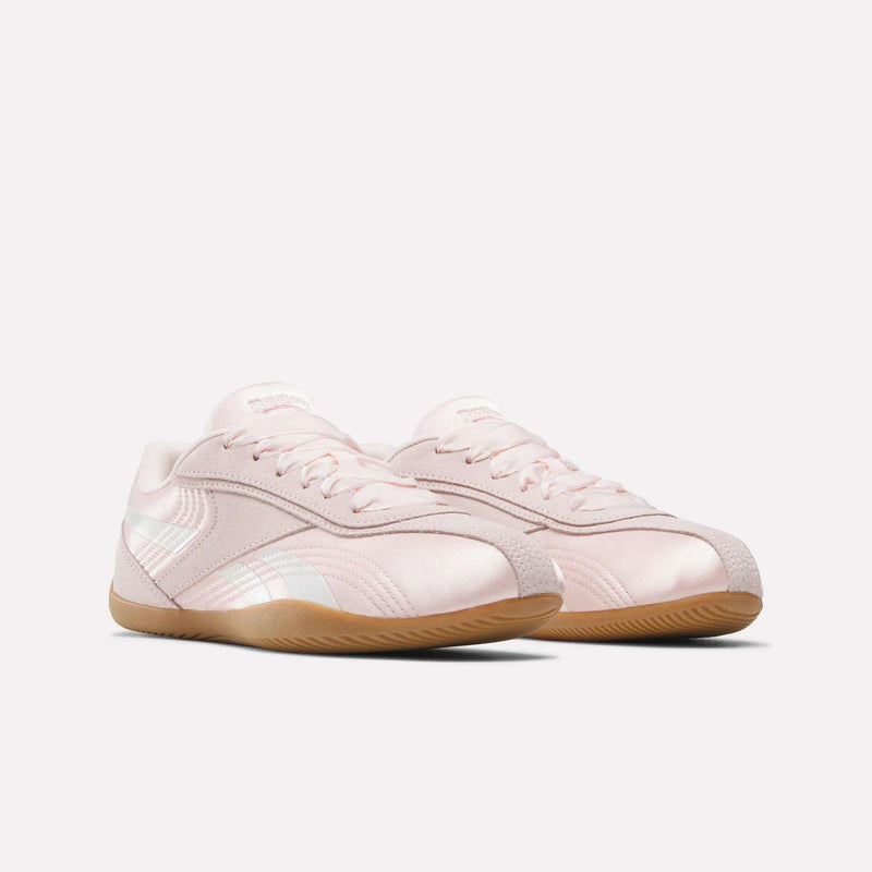 The Reebok Women's Ultra Lo Shoes feature a light pink color with white accents and gum rubber soles, offering sport-inspired style for women. Shown against a plain white background.