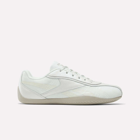 The Reebok Women's Ultra Lo Shoes are white low-tops with textured accents, white laces, and a light beige sole. Inspired by classic styles, they're pictured against a plain light backdrop.