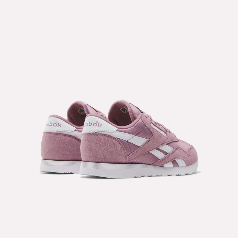 Women's Classic Nylon Shoes by Reebok shown in pink with white accents and soles, made of nylon and suede, displayed at an angle to highlight the back and sides against a plain white background.