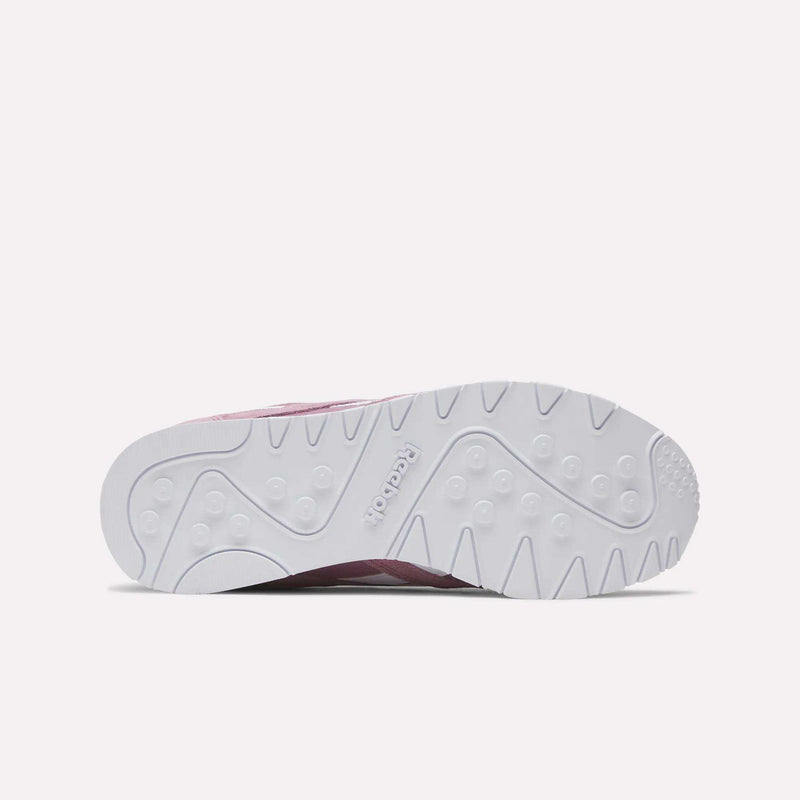 Bottom view of Reebok Women's Classic Nylon Shoes reveals a white rubber outsole with textured circular and wavy grip patterns, the embossed Reebok logo at center, and a glimpse of the pink retro nylon and suede upper.