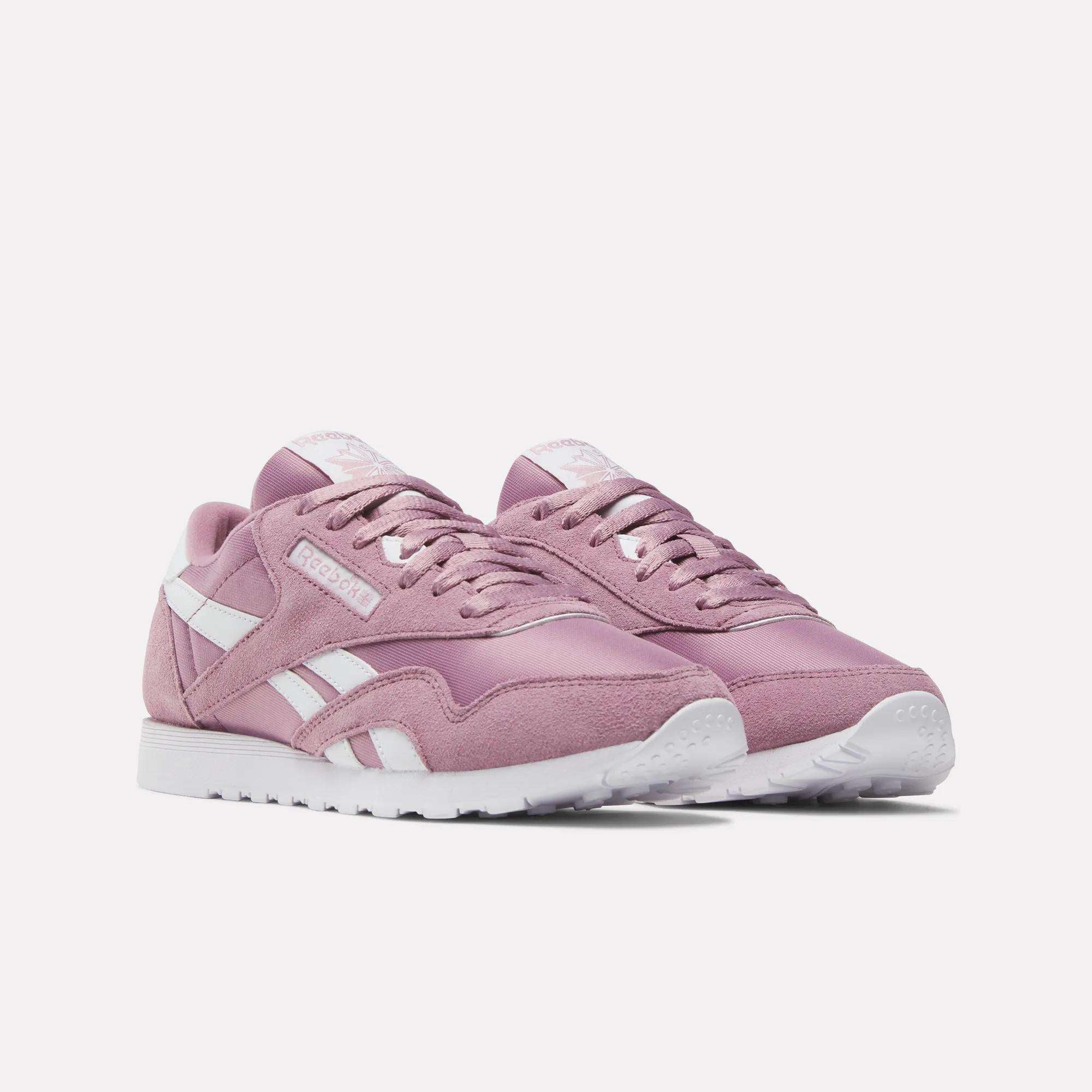 A pair of Women's Classic Nylon Shoes by Reebok in pink, with retro style, classic white soles, and side stripes are displayed side by side on a plain light background.