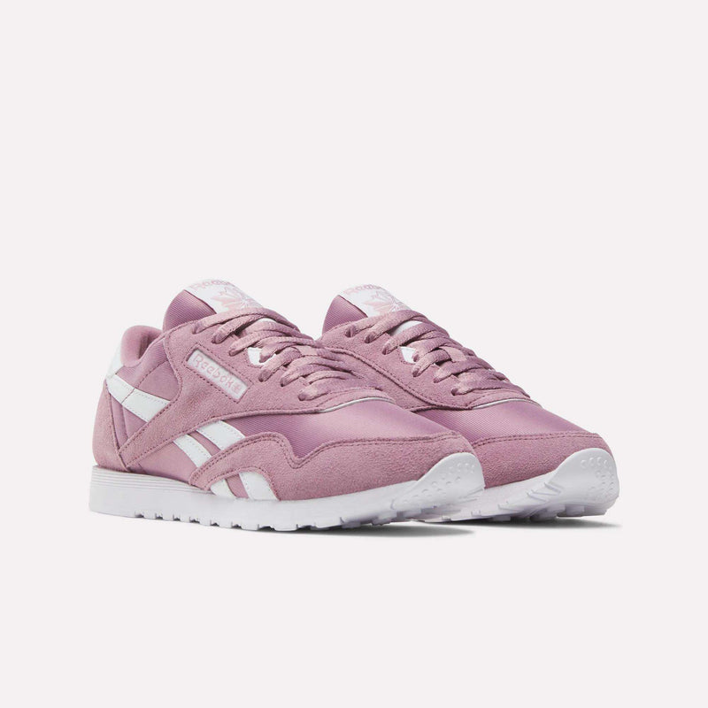 A pair of Women's Classic Nylon Shoes by Reebok in pink, with retro style, classic white soles, and side stripes are displayed side by side on a plain light background.