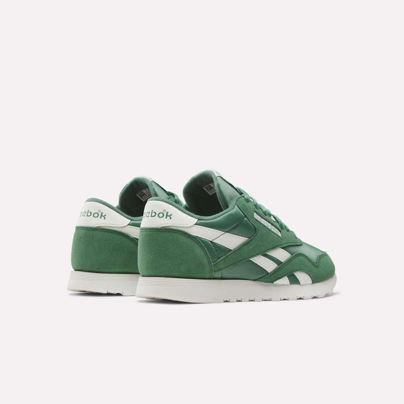 A pair of Women's Classic Nylon Shoes by Reebok, featuring green nylon and suede uppers, white soles and side stripes, with "Reebok" on the heel, displayed on a plain white background for a retro-inspired look.