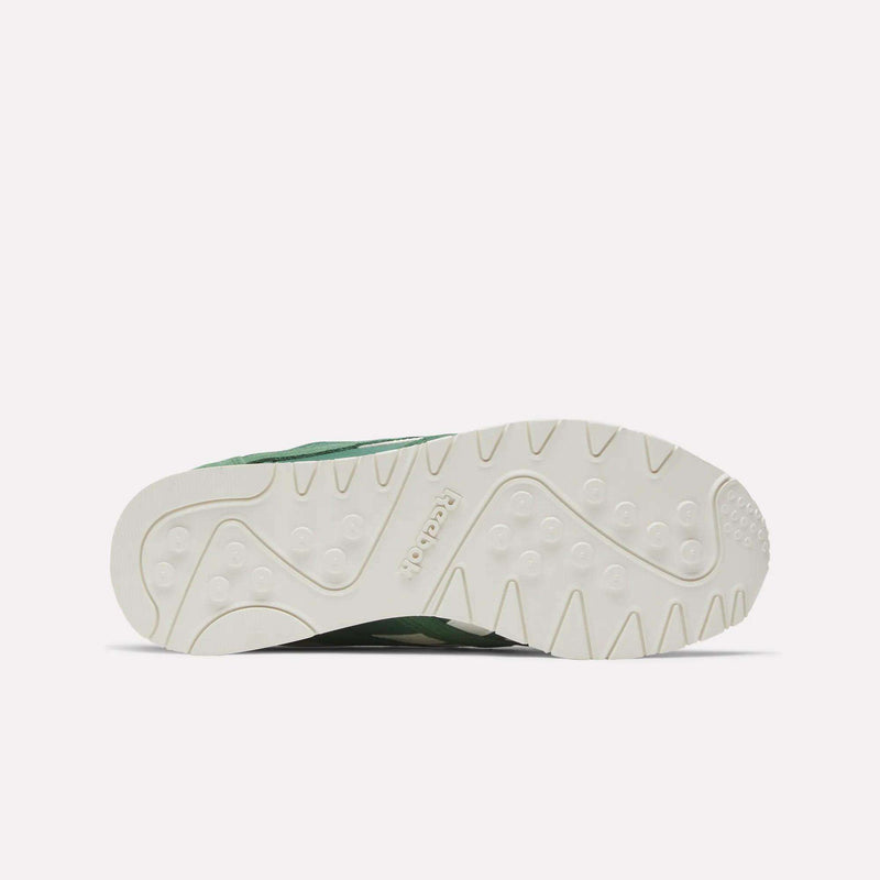The image displays the white rubber outsole of Reebok Women's Classic Nylon Shoes, viewed from below, with retro-style textured grip patterns and an embossed Reebok logo at the center.