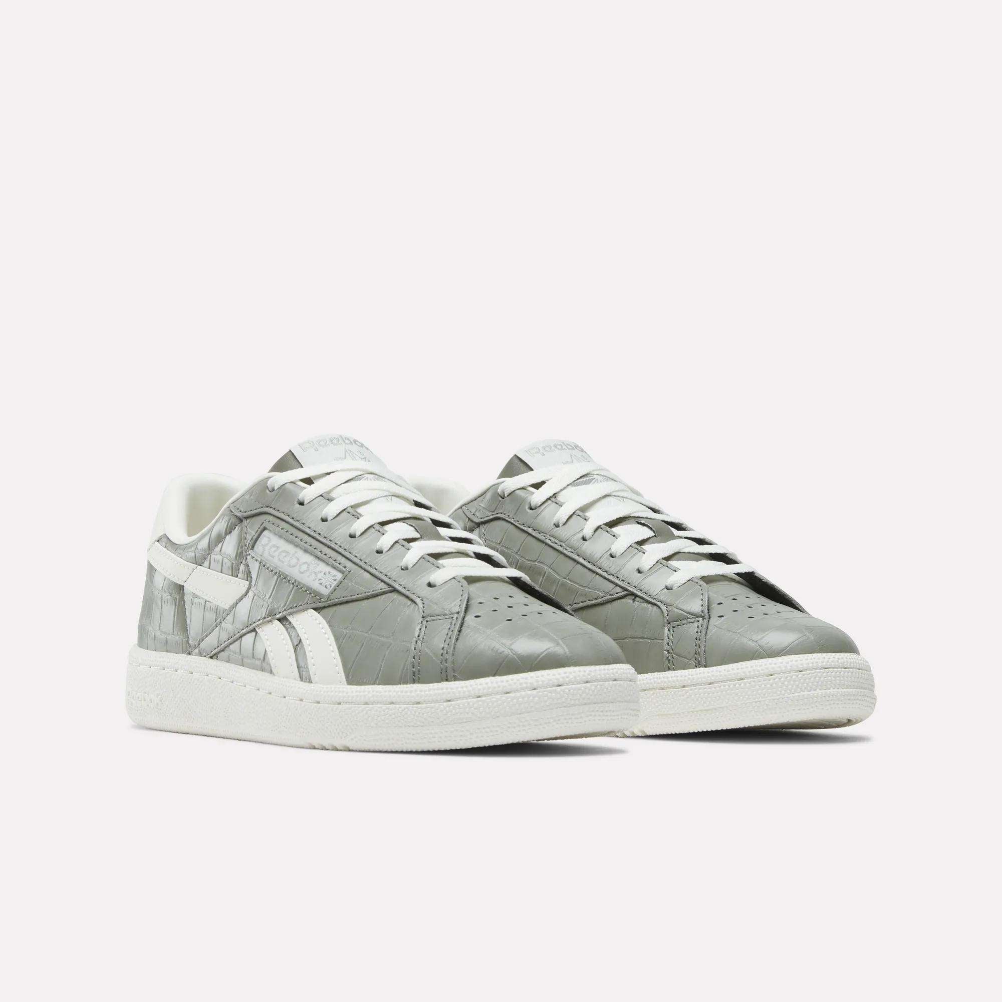 The Reebok Women's Club C Grounds UK Shoes feature a gray leather upper with white soles, laces, and side detailing, shown on a plain white background.