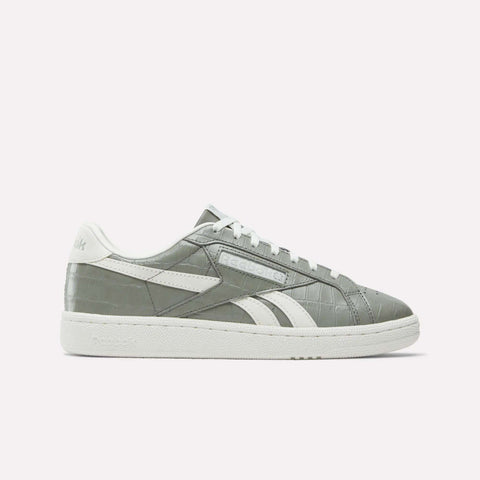 The Women's Club C Grounds UK Shoes by Reebok are gray court-inspired sneakers with white accents, premium leather details, a textured upper pattern, white laces, a white rubber sole, and the Reebok logo. Shown on a plain white background.