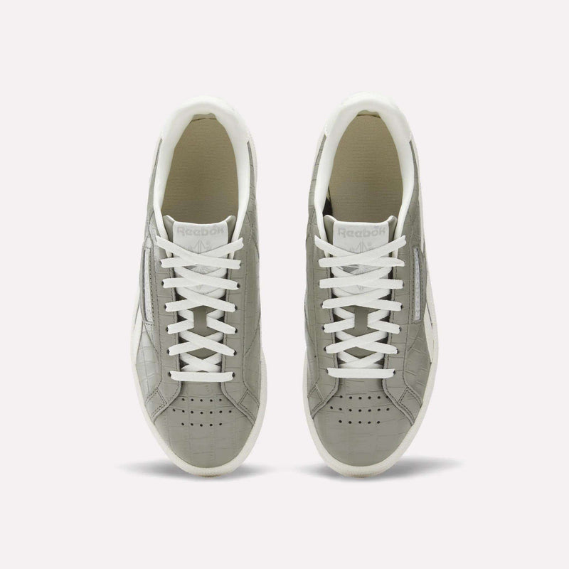 A pair of Reebok Women's Club C Grounds UK shoes in grey with white laces and soles, shown from above on a plain white background. These court-inspired shoes have perforated toes and a clean white inner lining.
