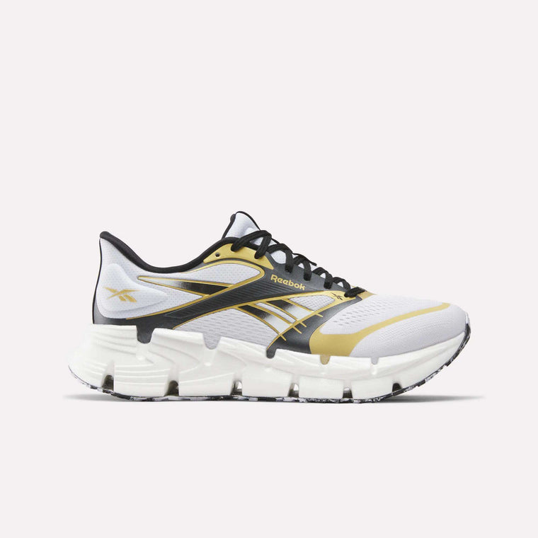 The Reebok FloatZig 2 Running Shoes in white with black and gold accents feature a chunky, segmented sole with Superfloat+ cushioning and black laces, shown from the side on a plain white background.