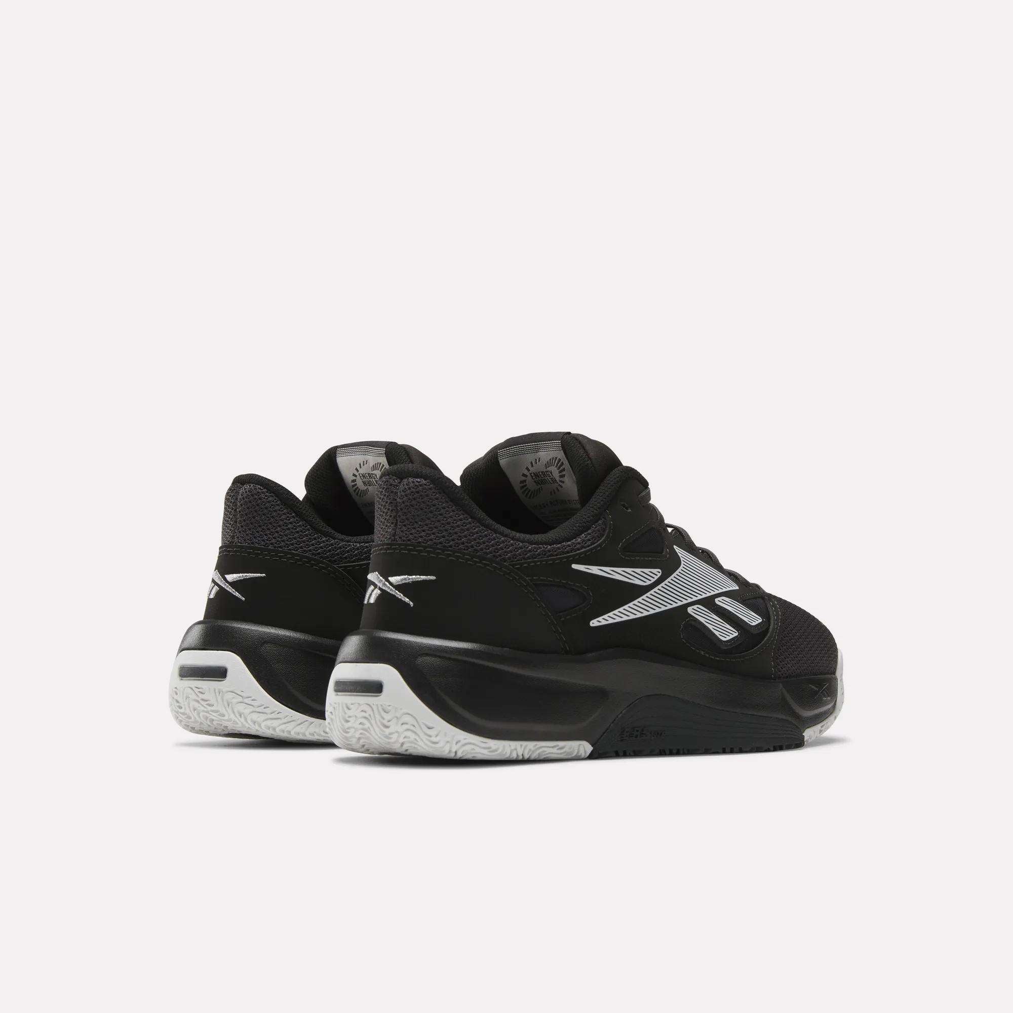A pair of Reebok Engine LT Shoes in black and white with silver accents, shown from the back and side on a plain light background.
