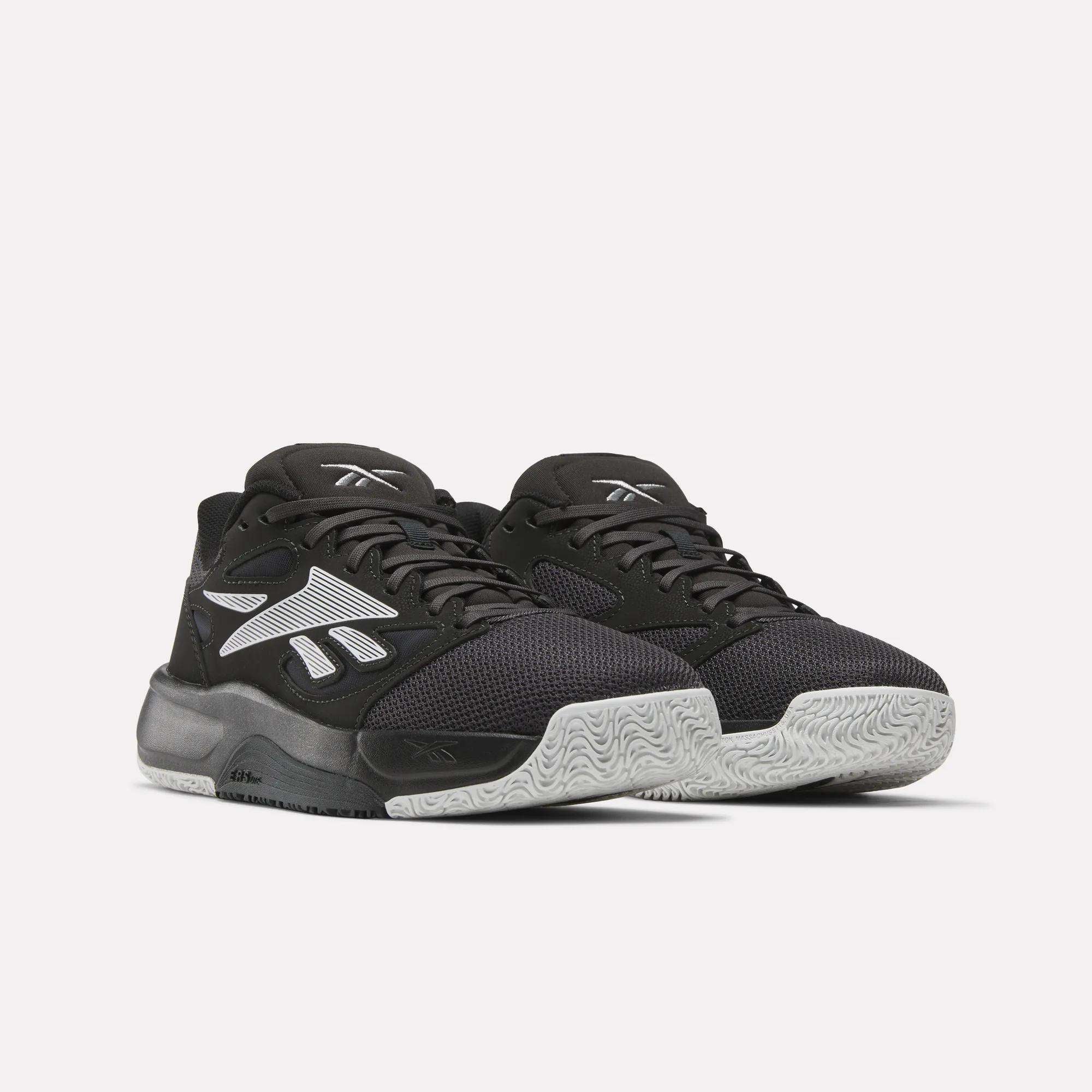 A pair of Reebok Engine LT Shoes with black mesh uppers, white textured soles, and bold white Reebok logos on the sides, shown on a plain light background.