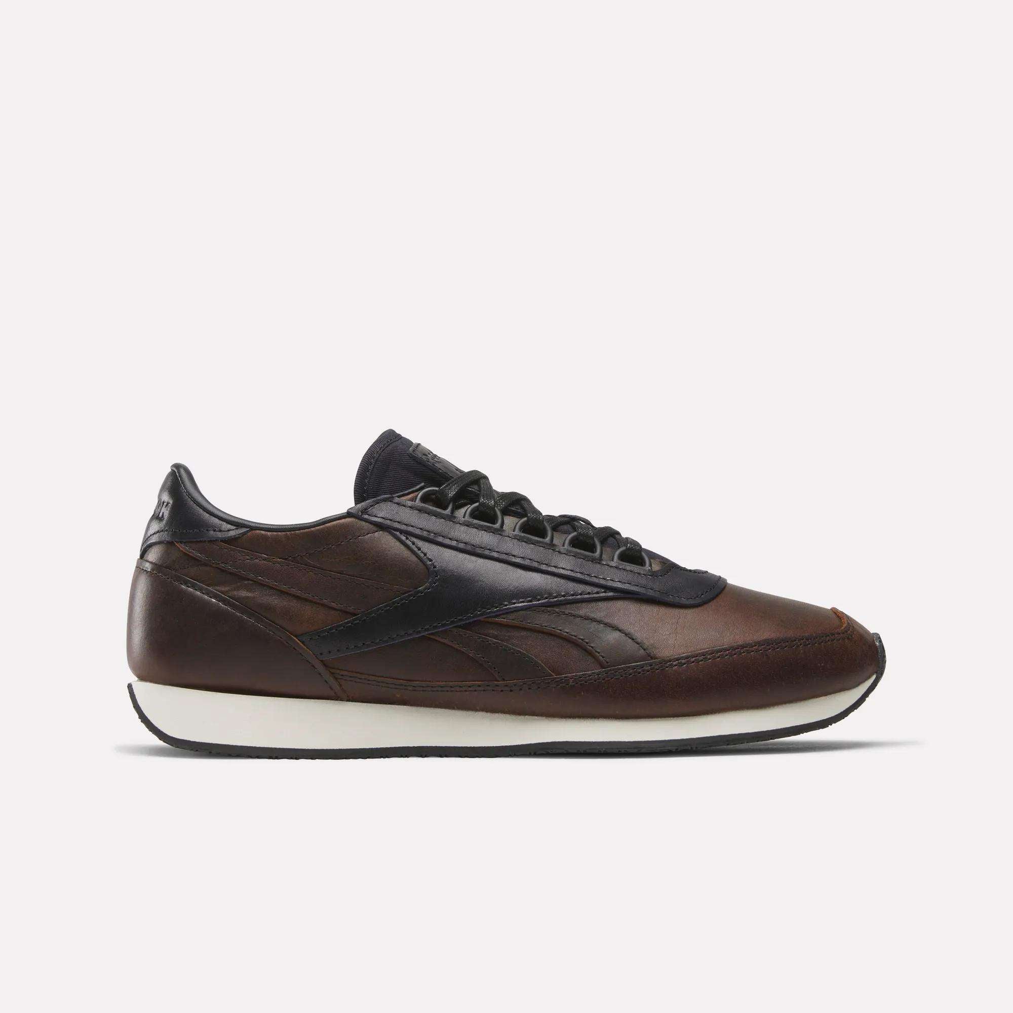 The Reebok Camargue x C.F. Stead Shoes, shown in side profile on a plain white background, feature brown full-grain leather with black accents and laces, a dark navy heel and sole detail, plus a white midsole in archival style.