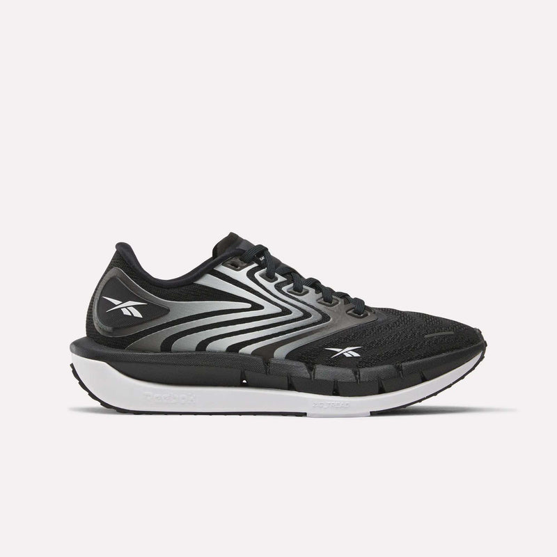 The Reebok Women's FloatZig Tread Running Shoe in black features white and gray wavy accents, a white midsole, black outsole, and breathable mesh—perfect for treadmill workouts. Side view shown on a plain white background.