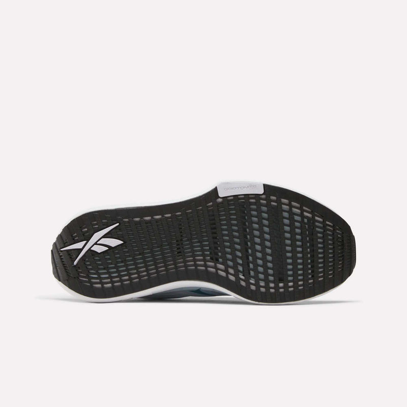 The image shows the black rubber outsole of Reebok Women's FloatZig Tread Running Shoes, with a white logo near the heel, a textured traction tread ideal for treadmill workouts, and a gray midfoot section labeled Floatride.